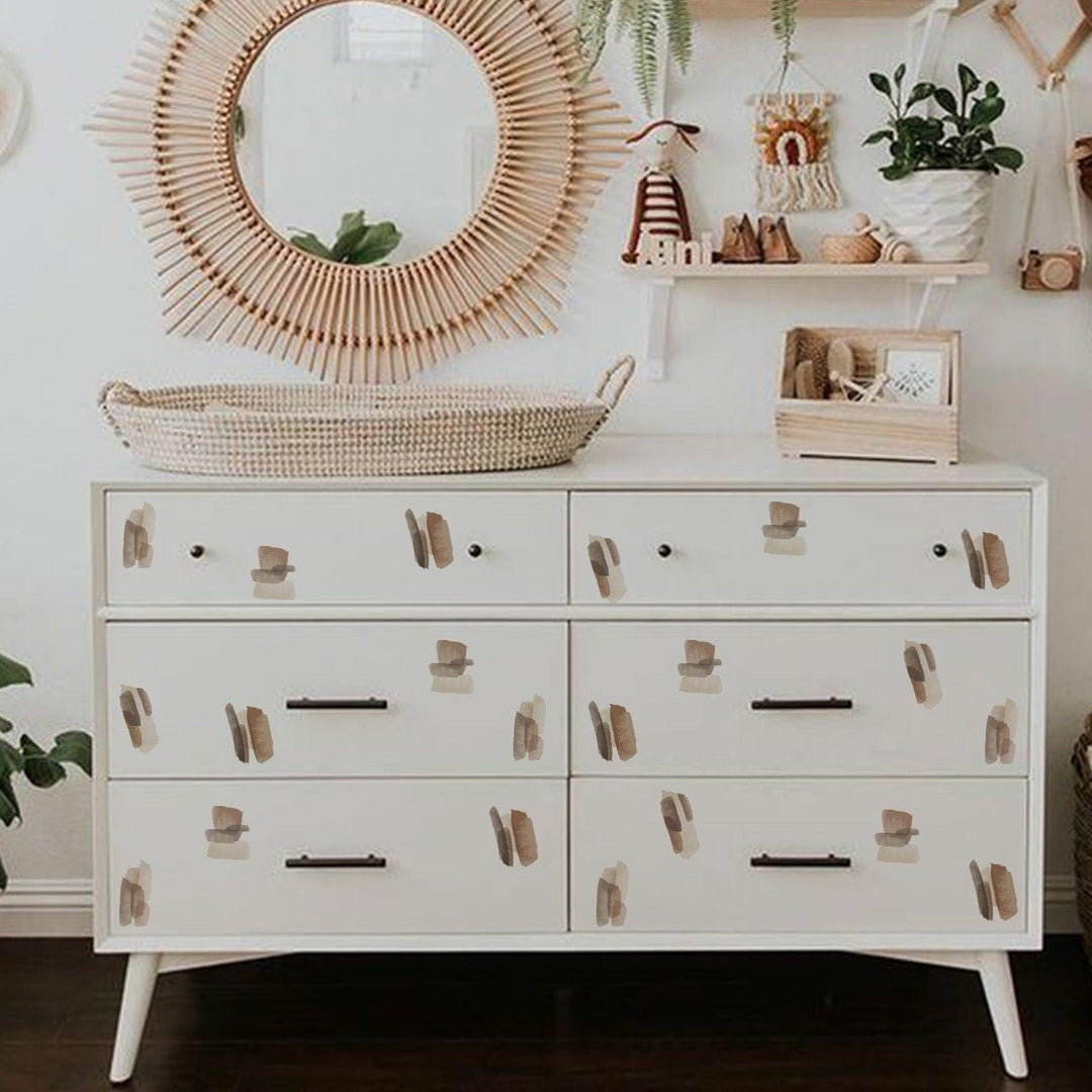 Brown and neutral color abstract lines wall decal stickers on draws of a white dresser in baby nursery